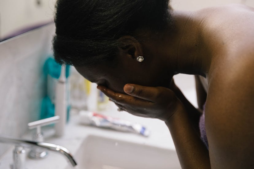 A pregnant woman with a fever, washing her face over a sink