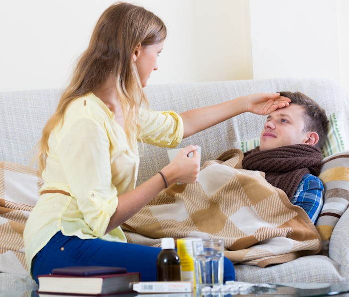 woman checks the forehead of a sick man