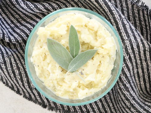 Mashed potatoes for one served in a green bowl and garnished with some greens