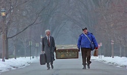 Two men carrying a big box down a road in "Planes, Trains, and Automobiles" Thanksgiving movie