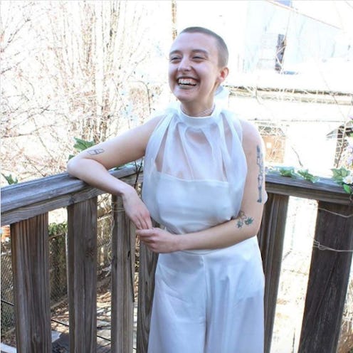 A young short-haired lady posing for a photo on a balcony