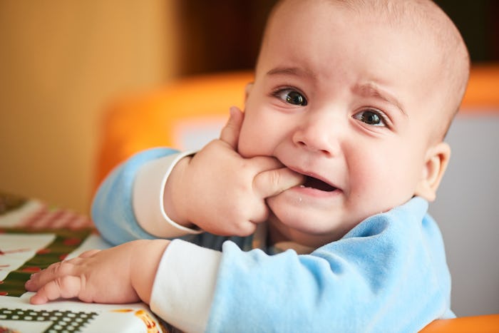 A baby who is teething puts his hand in his mouth in order to ease his pain