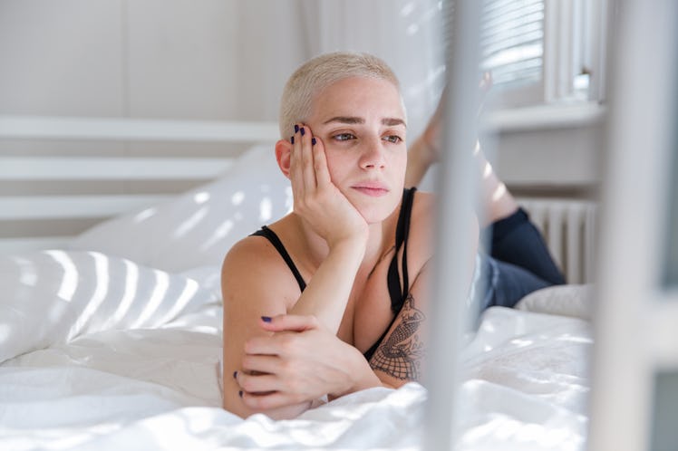 A woman lying in her bed with a worrisome expression as a depiction of signals a woman can experienc...