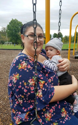 A mother holding her son and posing for a pic in the park