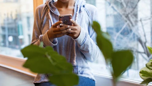 A woman looks at her phone behind a fiddle leaf fig plant. These subtle differences between bipolar ...