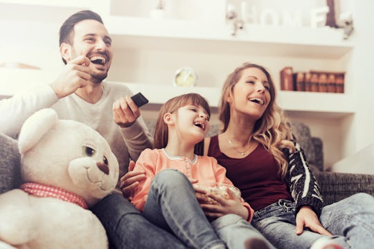 A family sitting on the couch watching netflix together and laughing out loud