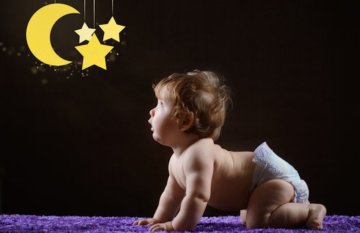 baby on hands and knees, looking at a star and moon mobile