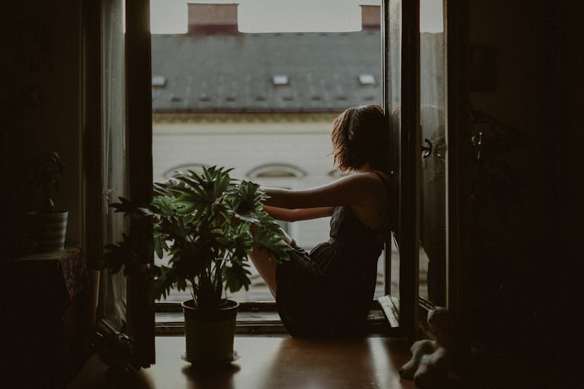 Anxious woman sitting on her window sill looking out onto the street