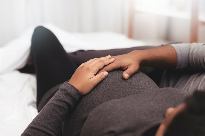 A pregnant woman that's Carrying High lying on a couch with her hand on her stomach