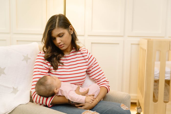 A mother suffering from postnatal insomnia, holding her baby in her arms while sitting down 