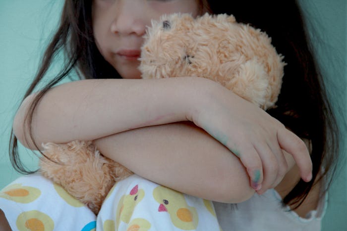 Child hugging teddy bear after having a nightmare