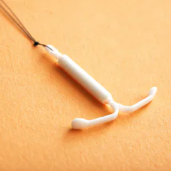 Close up of an IUD on an orange background