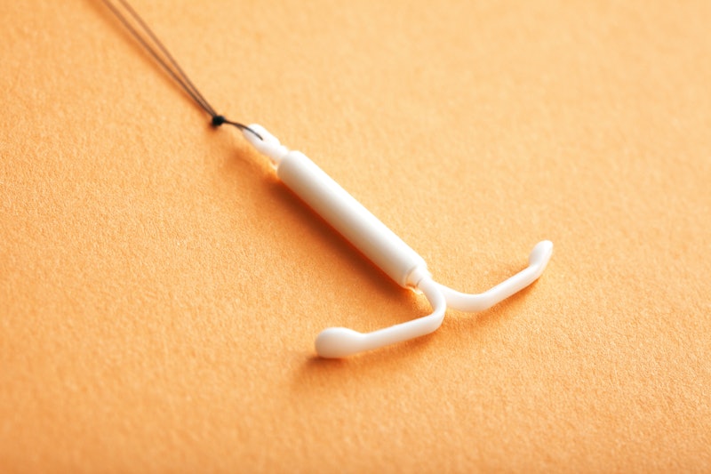Close up of an IUD on an orange background