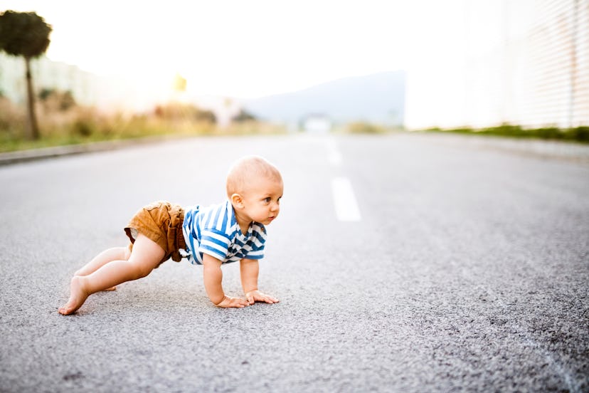 A baby crawling on the street.