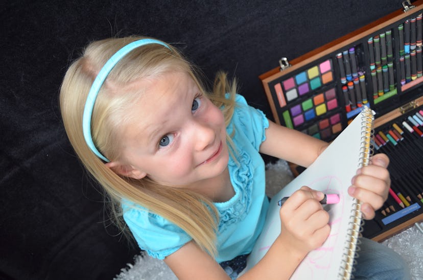  A blonde little girl coloring in her notepad.
