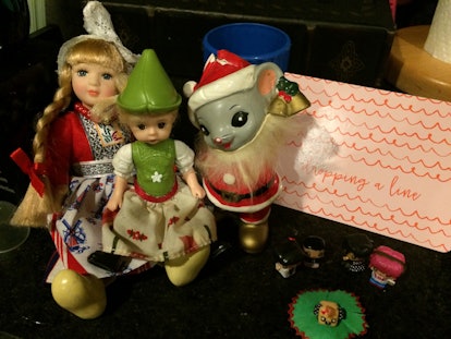 Blonde female doll, a green elf, and a mouse figures standing on the table
