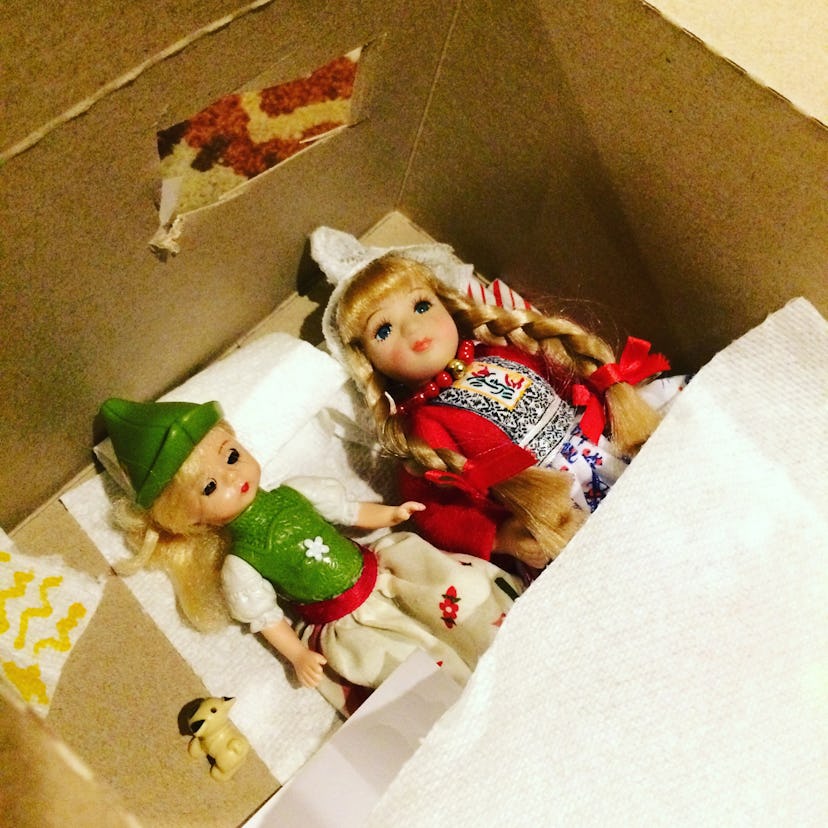 Two dolls laying in the cardbox 