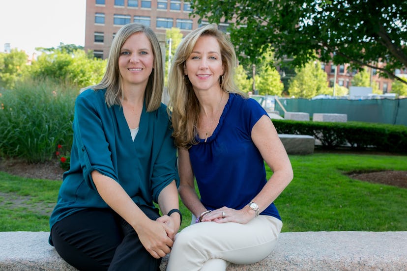 Michele Gay and Alissa Parker sit outside in front of a building and pose for a photo.