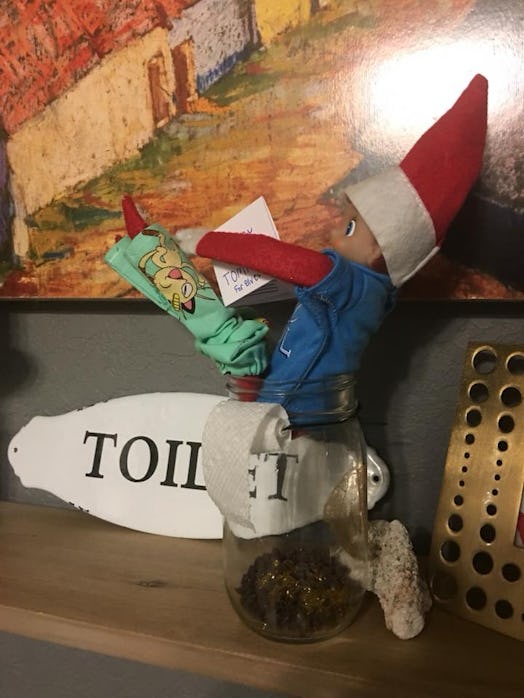An elf doll with a red hat and a toilet paper attached to it