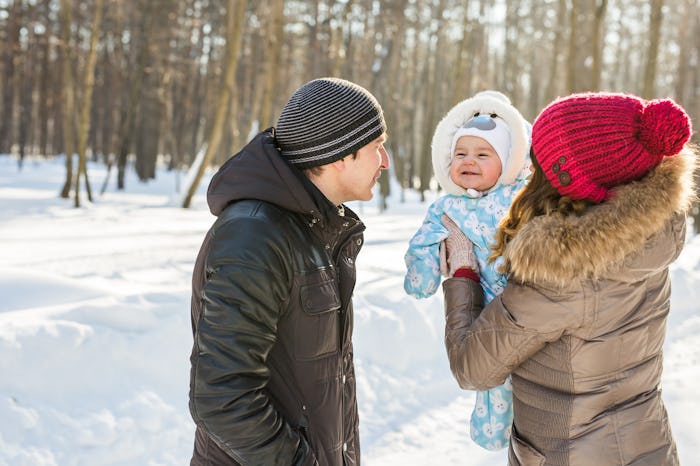 Parents with baby outside in snow, in a story about how to dress baby for cold temperatures.