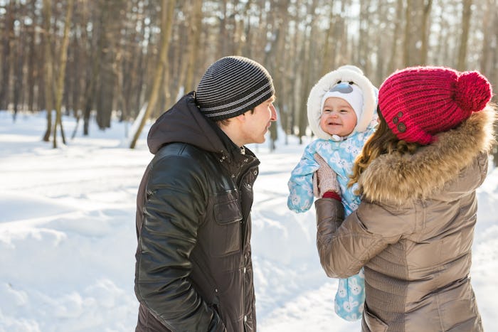 Parents with baby outside in snow, in a story about how to dress baby for cold temperatures.