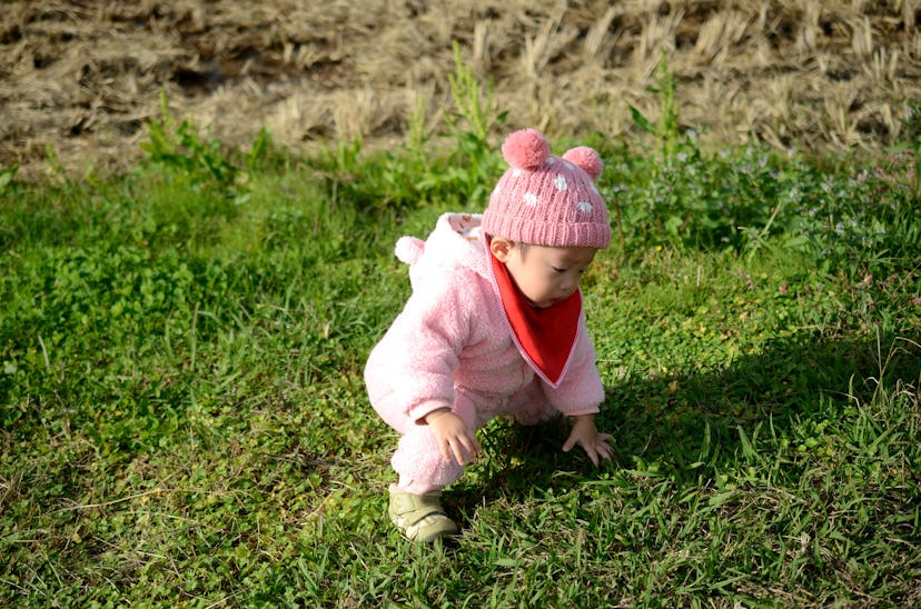 Baby with hat and coat playing outside, in a story about how to dress baby for cold temperatures.