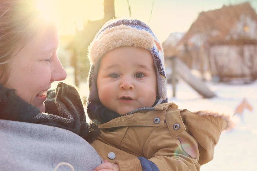 Baby outside in the snow with mom in a story about how to dress baby for cold temperatures.
