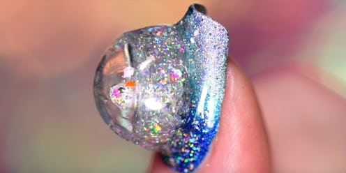 A snow globe styled nail manicure on a nail in blue and silver shades
