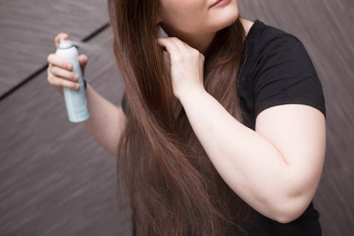A woman spraying her long brown hair after holiday styling