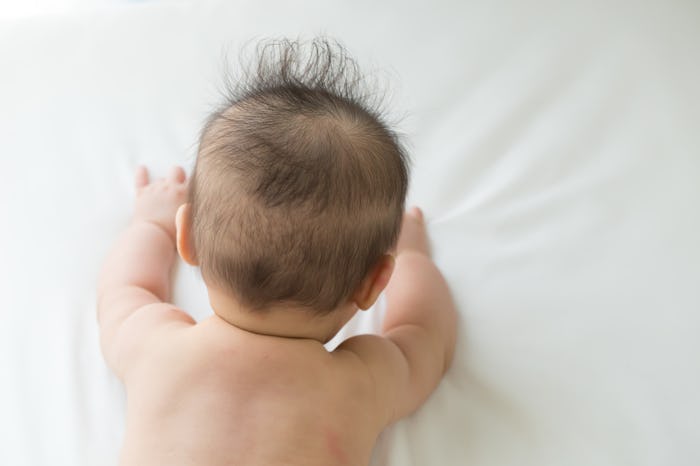 A newborn lying on its stomach on the white sheets
