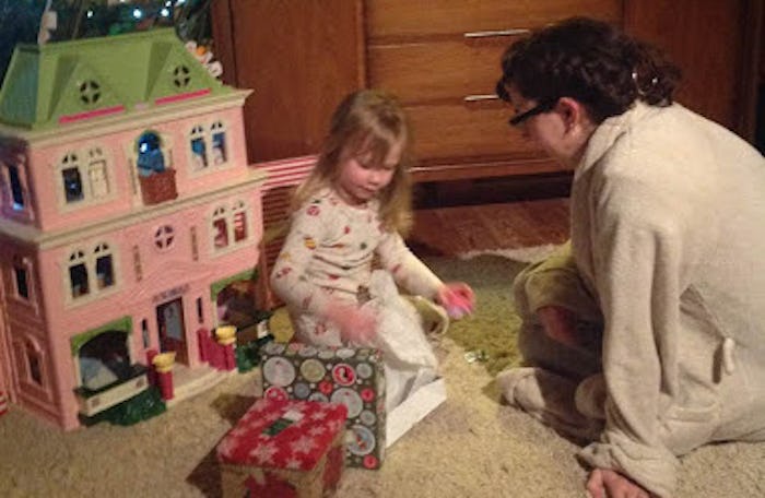 Emily F. Popek in the bathrobe that saved her postpartum, playing with her daughter and a dollhouse