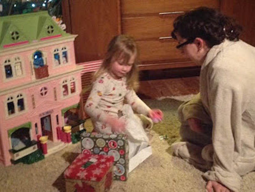 Emily F. Popek in the bathrobe that saved her postpartum, playing with her daughter and a dollhouse