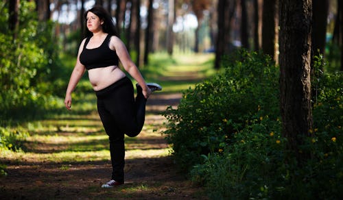 A woman stretching in the forest in order to accomplish her Postpartum Weight Loss