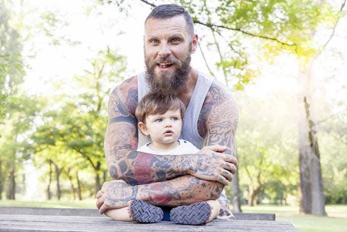 A tattooed father holding his son