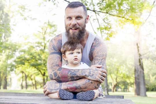 A tattooed father holding his son