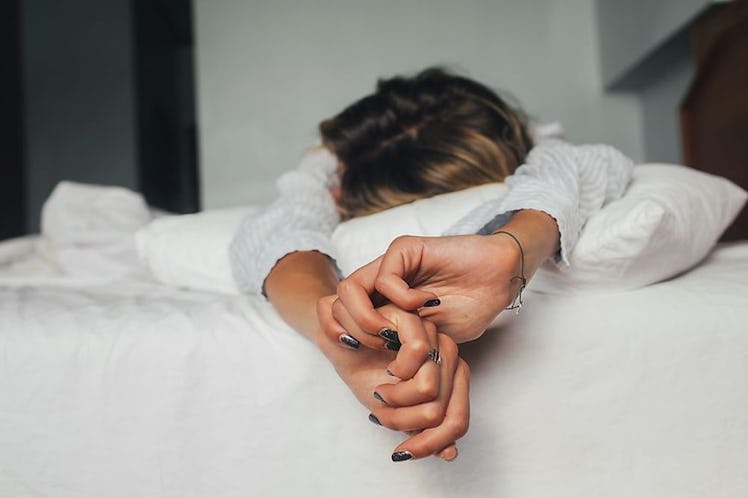 A woman lying before bed stomach down and stretching her arms forward to calm her busy brain