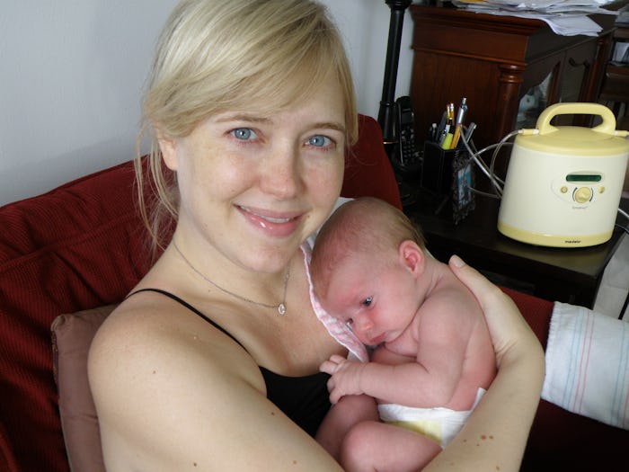 Caroline Hand in a black top smiling while holding her newborn on her chest