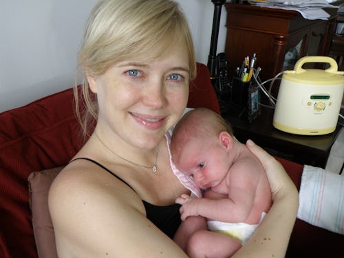 Caroline Hand in a black top smiling while holding her newborn on her chest
