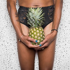 A person holds a pineapple in front of their crotch. Doctors explain how IUDs can affect your period...