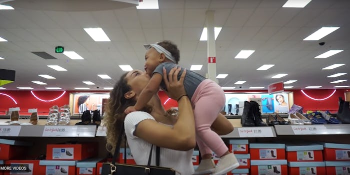 A millennial mom holds up and kisses her baby while at a target