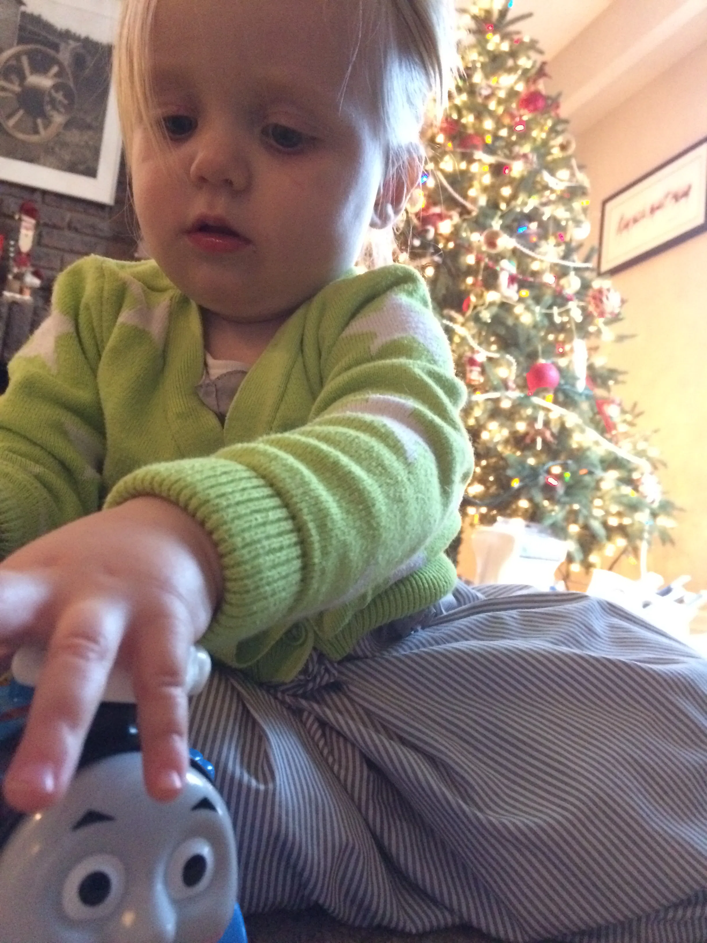 A little girl playing with a Thomas train toy