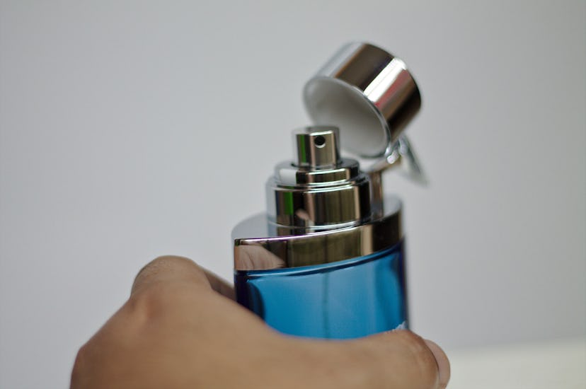 A hand holding a bottle of drugstore cologne