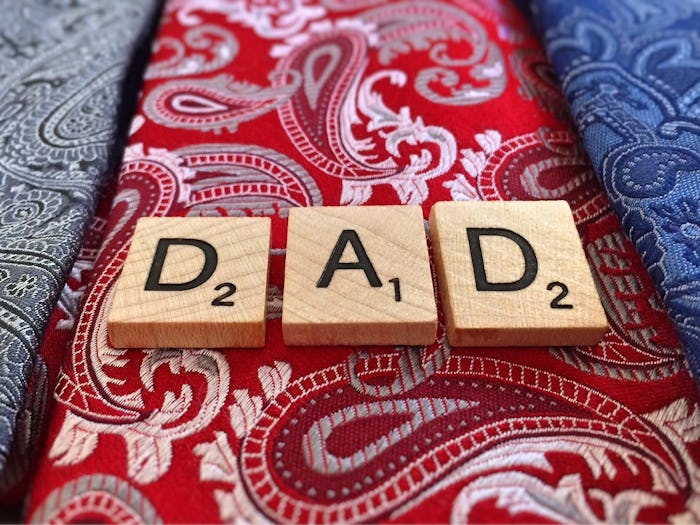 Three wooden scrabble elements forming the word 'DAD' on a red tie