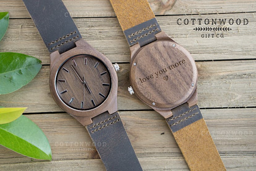 Two engraved leather and wood watches sitting on the table