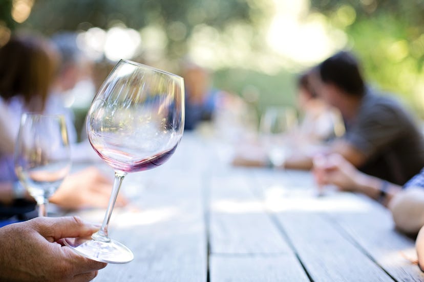 A group of people sitting at the table where the focus is on the wine glass