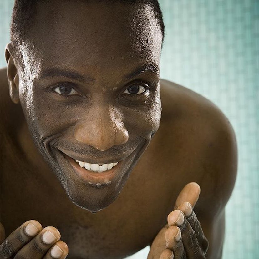 A photo of a black man smiling and being up close to the camera after washing his face