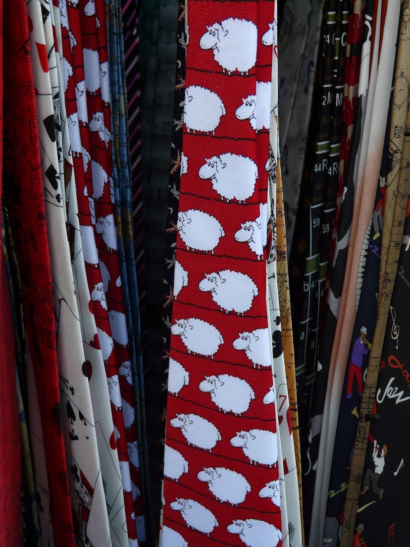 A red tie with a sheep-pattern hanging among other novelty ties