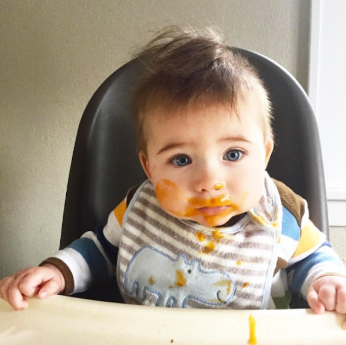 A toddler sitting in a feeding chair with rice cereal smeared on his face