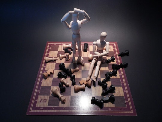 Scattered chess pieces and two figures on a chess box