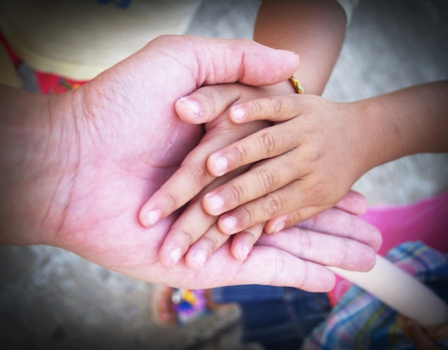 An adult hand with two kids' hands holding them.